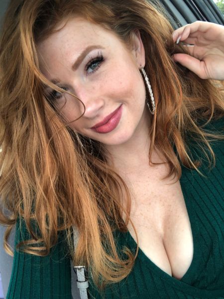 YouTuber Abigale  posing wearing a green see-through sweater in a blonde hair.